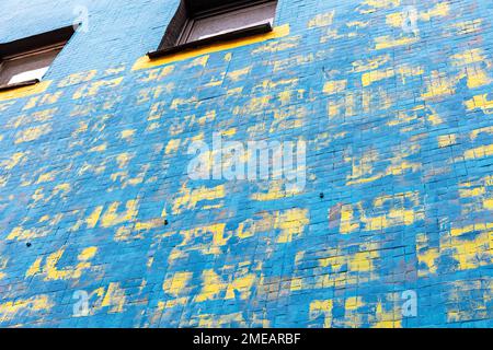 Blau bemalte Betonwand mit abstrakter, farbenfroher Straßenkunst Stockfoto