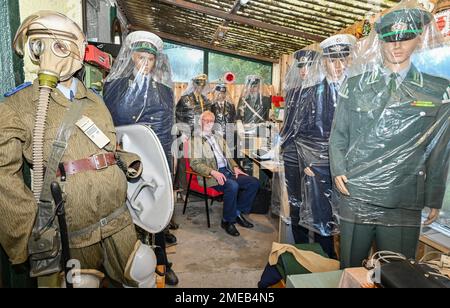 Eggersdorf, Deutschland. 19. Januar 2023. Christian Paul, Sammler, sitzt in seinem kleinen privaten Museum unter verschiedenen Figuren mit Uniformen, die in Plastiktüchern verpackt sind. Mit einer Polizei begann Lada vor etwa 15 Jahren, was sich jetzt zu einer umfangreichen Sammlung von Blaulicht entwickelt hat. Viele Uniformen und noch mehr alte Technologie, es gibt den Sammler Christian Paul zu bewundern. (Zu dpa-KORR „Täuschungsgeist – wenn Oldtimer der DDR renoviert werden“) Kredit: Patrick Pleul/dpa/Alamy Live News Stockfoto