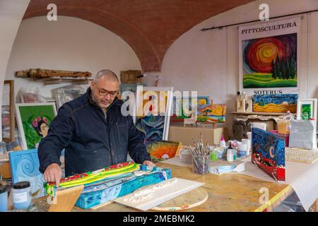 Der Handwerker/Künstler Salvatore Ferrante, „Soterus“, in seinem Atelier; bekannt für seine einzigartigen handgeschnitzten und handgemalten Holzbilder, Toskana, Italien. Stockfoto