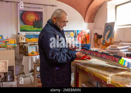 Der Handwerker/Künstler Salvatore Ferrante, „Soterus“, in seinem Atelier; bekannt für seine einzigartigen handgeschnitzten und handgemalten Holzbilder, Toskana, Italien. Stockfoto