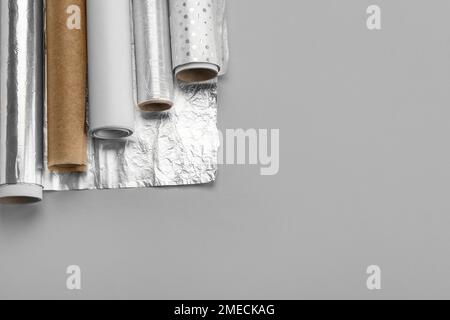Rollen aus Aluminiumfolie und Backpapier auf grauem Hintergrund Stockfoto