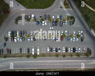 Belebter großer moderner Parkplatz mit symmetrischen Straßen Reihen von Parkbuchten viel Symmetrie und Farben aus der Vogelperspektive von der Drohne nach oben mit Blick nach unten. Stockfoto