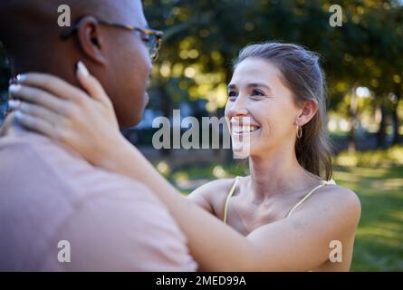 Zwischenmenschliche Liebe, Paare und Parken für Date, Sommerurlaub und Outdoor Wellness mit Umarmung, Sorgfalt und Engagement. Glückliche, junge und vielfältige Menschen in A Stockfoto