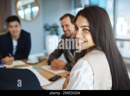 Sie bringt immer großartige Energie und Ideen in unsere Meetings mit. Porträt einer jungen Geschäftsfrau, die in einem Meeting in einem Büro sitzt. Stockfoto