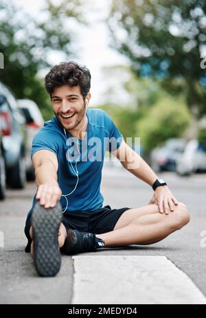 Kein Wunder, dass mich die Leute komisch ansehen. Ein sportlicher junger Mann, der sich beim Sport im Freien die Beine vertreten lässt. Stockfoto