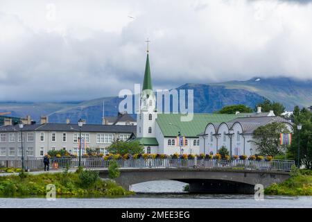Reykjavik, Island - 29. Juli 2022: Frikirkja mit Brücke im Vordergrund und Bergen im Hintergrund Stockfoto