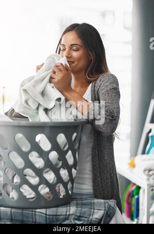 Ich habe meine Arbeit ordentlich gemacht, die Wäsche riecht toll. Eine attraktive junge Frau, die ihre Wäsche zu Hause macht. Stockfoto