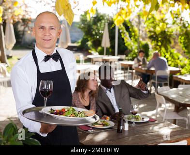Nach Kellner bedient Kunden in einem Open-air Restaurant Stockfoto