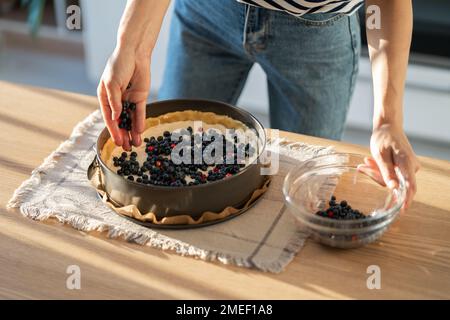 Nahaufnahmen einer Hausfrau, die Kuchen zubereitete und frische Blaubeeren für den festlichen Tisch hinzufügte Stockfoto