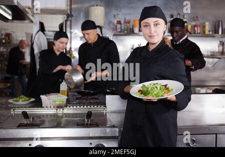 Zuversichtlich Köchin mit einem Team von Köchen im Restaurant Küche Stockfoto