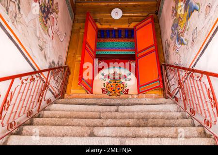 Treppen führen zu einer bemalten Tür einer tibetischen Gebetshalle im Kumbum Champa Ling Kloster nahe Xining, China Stockfoto