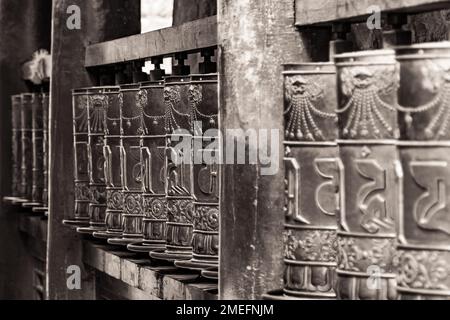 Schwarzweißbild mit Fluchtpunkt-Perspektive auf großen Gebetsrädern in einem tibetischen Kloster, Xining, China Stockfoto