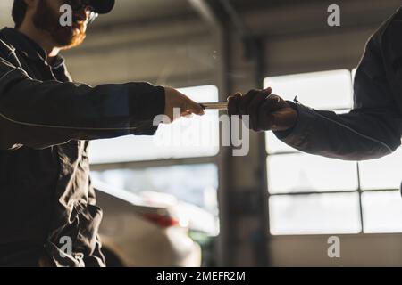 Schuss aus niedrigem Winkel. Zwei Hände männlicher Mechaniker mit einem Schraubenschlüssel. Werkstattkonzept. Hochwertiges Foto Stockfoto