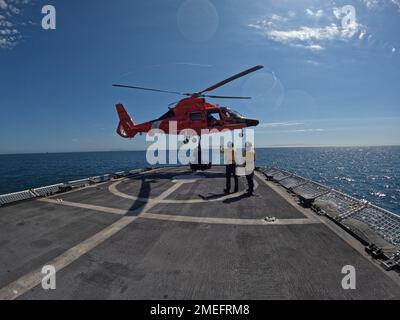 Ein Helikopter-Luftteam an Bord eines MH-65 Dolphin Hubschraubers von der Air Station Humboldt Bay führt eine vertikale Auffüllung mit dem Coast Guard Cutter Steadfast (WMEC 623) durch, während Steadfast am 16. August 2022 den Pazifischen Ozean patrouilliert. Standhaft kehrte am 3. Oktober 2022 nach einer 55-tägigen Drogenstreife in ihr Astoria-Heimathafen zurück. Foto der US-Küstenwache. Stockfoto