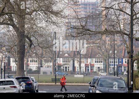 Ein Postbote von Royal Mail beliefert Postsendungen auf der Ferndene Road, wo am 23. Januar 2023 in London, England, in Loughborough Junction ein neues Hochhausgebäude in Higgs Yard im Bau ist. Stockfoto
