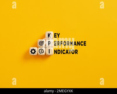 Das Akronym KPI und Key Performance Indicator Text auf Holzwürfeln auf gelbem Hintergrund. Stockfoto