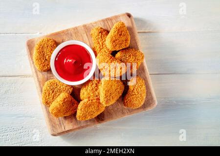 Chicken Nuggets mit bbq-Sauce auf rustikalem Holzhintergrund, Top Shot. Eine knusprige Vorspeise in einem Restaurant, Fingerfood Stockfoto
