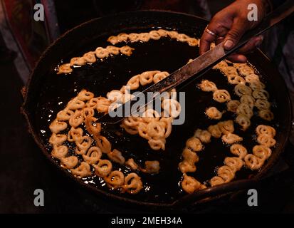 Jalebi ist ein sehr beliebter süßer Snack in Süd- und Westasien, Afrika und Mauritius. Es gibt viele Namen, einschließlich Jilapi, Zelepi, Jilebi, Jilipi, Zulbia, jerry, Mushabak, z’Labia oder Zalabia. Die südasiatische Sorte wird durch Frittieren von maida-Mehlteig (einfaches Mehl oder Allzweckmehl) in Brezel- oder Kreisform hergestellt, der dann in Zuckersirup getränkt wird. Jalebi wird mit Quark oder Rabri (in Nordindien) zusammen mit optionalen anderen Geschmacksrichtungen wie Kewra (duftendes Wasser) gegessen. Tehatta, Westbengalen, Indien. Stockfoto