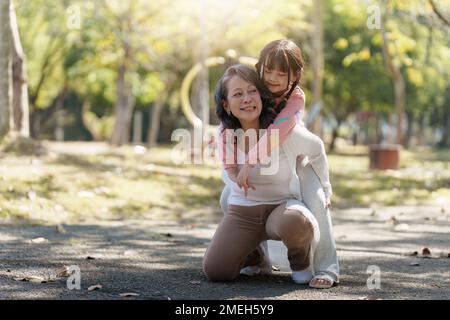 Asiatische Großmutter und Enkelin umarmen sich gemeinsam im Park. Hobbys und Freizeit, Lifestyle, Familienleben, Happiness Moment Konzept Stockfoto