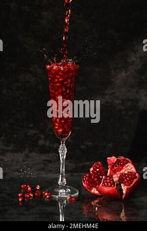 Granatapfelwein im Glas auf schwarzem Hintergrund Stockfoto