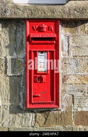 Hellrote V R Post Box an einer Wand am Bahnhof Bere Alston in Devon. Pist Box Nummer PL20 443. Stockfoto