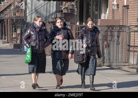 Orthodoxe jüdische Schulmädchen gehen zusammen nach Hause und tragen den gleichen karierten Rock, die Schuluniform. In Brooklyn, New York, 2023 Stockfoto