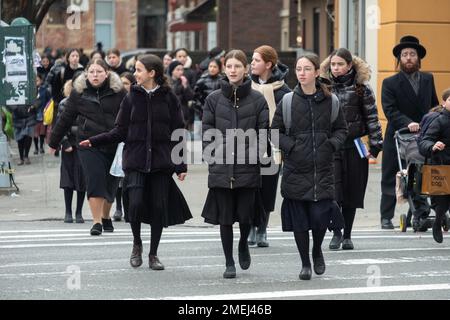 Eine Straßenszene mit ultraorthodoxen jüdischen Mädchen, die von der Schule nach Hause fahren. Alle waren bescheiden gekleidet in langen schwarzen Röcken. In Brooklyn, New York. Stockfoto
