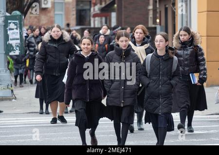 Eine Straßenszene mit ultraorthodoxen jüdischen Mädchen, die von der Schule nach Hause fahren. Alle waren bescheiden gekleidet in langen schwarzen Röcken. In Brooklyn, New York. Stockfoto