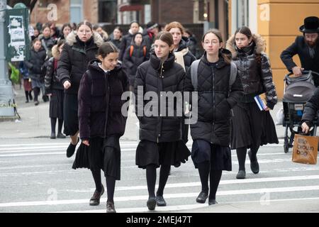 Eine Straßenszene mit ultraorthodoxen jüdischen Mädchen, die von der Schule nach Hause fahren. Alle waren bescheiden gekleidet in langen schwarzen Röcken. In Brooklyn, New York. Stockfoto