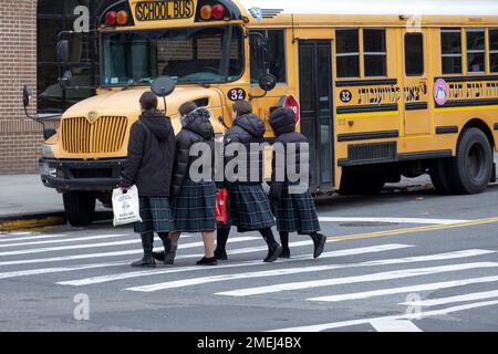 4 anonyme orthodoxe jüdische Schulmädchen gehen zusammen nach Hause und tragen den gleichen karierten Rock, die Schuluniform. In Brooklyn, New York, 2023 Stockfoto