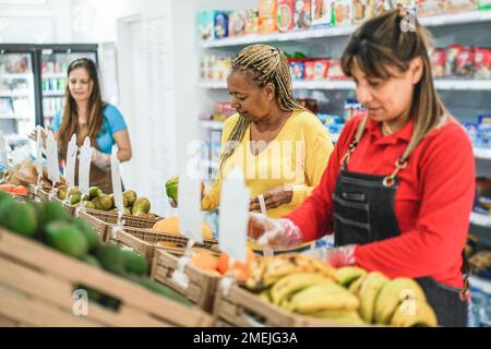 Weibliche Kundin, die Bio-Lebensmittel auf dem Markt für Öko-Frischwaren kauft – Fokus auf afrikanische Frau, die Obst in der Hand hält Stockfoto