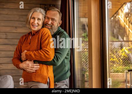 Ein Mann umarmt seine Frau und beide sehen glücklich und zufrieden aus Stockfoto