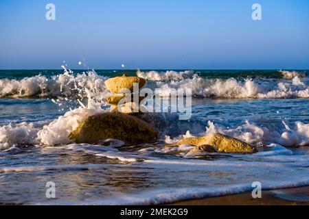 Ein Felskirschen, Wellen und Spray am Strand von Capo Bianco. Stockfoto