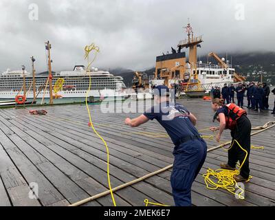 Crewmitglieder, die während der Olympischen Spiele in der Küstenwache Juneau am 17. August 2022 eine Wurflinie werfen. Die Olympischen Spiele der Booy Tender fanden in Juneau, Alaska, im Rahmen der jährlichen Booy Tender Round-Up der Küstenwache statt. Booy Tender Round-Up ist eine einwöchige Veranstaltung, bei der die Teilnehmer eine spezielle Schulung erhalten, Gespräche zur Verbesserung des Betriebs führen und eine Booy Tender Roundup Olympiade veranstalten können, um ihre Seemannsfertigkeiten zu testen. Crews von Coast Guard Cutters Kukui, Cypress, Fir, Anthony Petit und Elm nahmen an mehreren Veranstaltungen Teil, darunter der Kettenzug Stockfoto