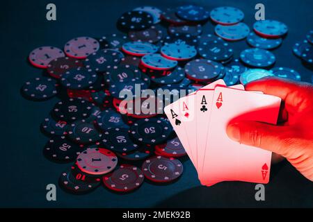 Männerhände halten Karten, Asse im Hintergrund spielen Chips Stockfoto