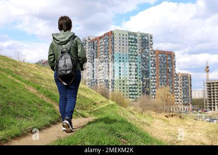 Frau auf Green Hill sieht sich die neuen Gebäude und den Baukran an, Wohnviertel in ökologisch sauberem Gebiet. Bauindustrie Stockfoto