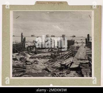 Drei Tage nach der Invasion von Tarawa ist der Strand voller Trümmer und Zerstörung. Das Foto zeigt zwei japanische Landungsboote, die an einem Schiffsreparaturdepot angelandet sind, mit Küstenwache bemannten LSTs vor der Küste, die die Nachwirkungen der intensiven Schlacht festhalten. Stockfoto