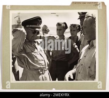 Ein deutscher Offizier nimmt beiläufig sein Eiserne Kreuz ab, um es neugierigen US-Küstenwachen zu zeigen, die ihn zusammen mit anderen deutschen Gefangenen aus Nordafrika in die USA gebracht hatten. Das Bild zeigt die Begegnung zwischen der Küstenwache und Kriegsgefangenen. Stockfoto