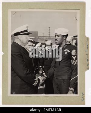 Foto des Küstenwächters Clarence W. Dabney mit der Purple Heart Medal for Wunds received in Action. Der Küstenwächter verlieh Purple Heart: Verwundet von Japanern, blieb er bei seiner Waffe. Coast Guardsman Clarence W. Dabney (rechts), Ship's Cook, 49 Leach Street, NW, Atlanta, Georgia, erhält die Purple Heart Medaille für Wunden, die an Bord einer von der Küstenwache bemannten LST im Südpazifik im Einsatz waren. Alle Hände sind als Lieutenant Commander W.H. verstümmelt Maybaum, Befehlshaber der LST, hält die Präsentation im Namen des Befehlshabers der USA Küstenwache. Die Zeremonie fand statt Stockfoto