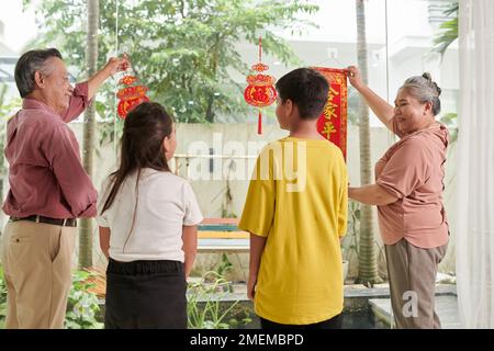 Großeltern und Enkelkinder dekorieren das Haus zum chinesischen Neujahr Stockfoto