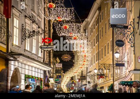 SALZBURG, ÖSTERREICH - 29. DEZEMBER 2022: Berühmte historische Getreidegasse, Einkaufsstraße zur Weihnachtszeit mit Lichterdekoration Stockfoto