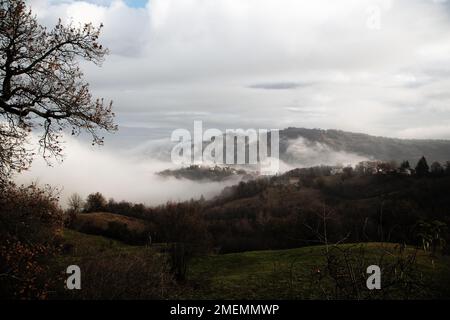 Landschaft des nebelverhangenen Dorfes auf einem Hügel, toskanisch-emilianische Apenninen, Italien Stockfoto