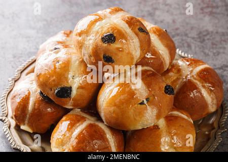 Frisch gebackene Osterbrötchen mit Sultaninen auf dem Teller auf dem Tisch. Horizontal Stockfoto