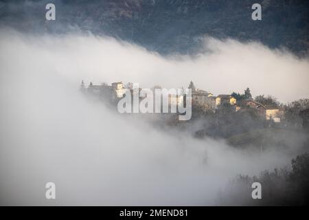 Landschaft des nebelverhangenen Dorfes auf einem Hügel, toskanisch-emilianische Apenninen, Italien Stockfoto