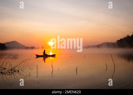 Frauen auf Kajak-Reihen im Stausee während des Sonnenaufgangs, Harirak Waldpark Huai Nam man Stausee Loei Thailand 21. Januar 2023 Stockfoto