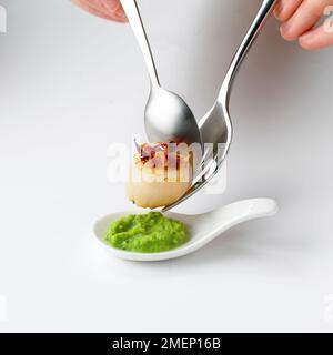 Einen chinesischen Löffel mit Erbsen und Jakobsmuscheln Stockfoto