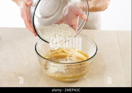 Rhubarb und Ingwer auf dem Kopf backen und gesiebtes Mehl in den Teig in der Schüssel geben Stockfoto