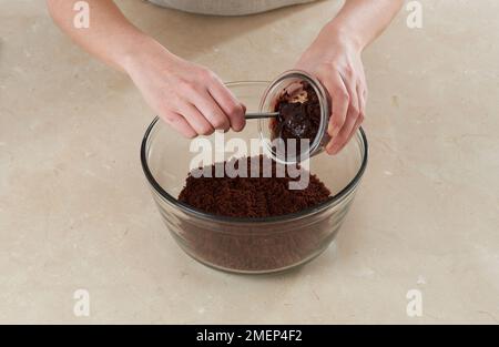 Ich mache Schokoladen-Toffee-Kuchenbälle und füge Zuckerguss zu Kuchenkrümeln hinzu Stockfoto