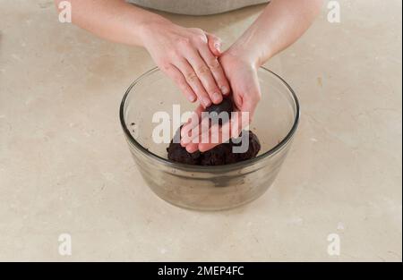 Schokoladen-Toffee-Kuchenbälle, die sich mit den Händen zu Bällen mischen Stockfoto