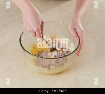 Herstellung von Schokoladen-Fudge-Kuchenbällen, Falten von Kakao, Mehl und Backpulver zu Kuchenteig Stockfoto